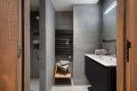 Modern bathroom with gray tile, a walk-in shower, and a floating vanity with a sleek black finish.