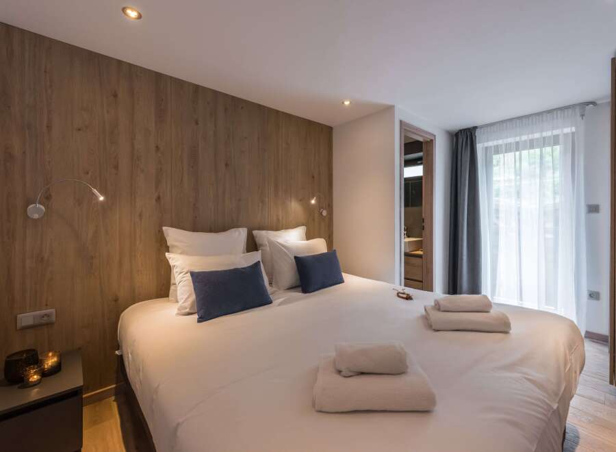This cozy bedroom features a stylish wooden accent wall and a comfortable bed with plush pillows.