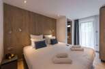This cozy bedroom features a stylish wooden accent wall and a comfortable bed with plush pillows.