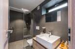 This modern bathroom features a sleek, minimalist design with dark gray tiles and a glass shower enclosure.