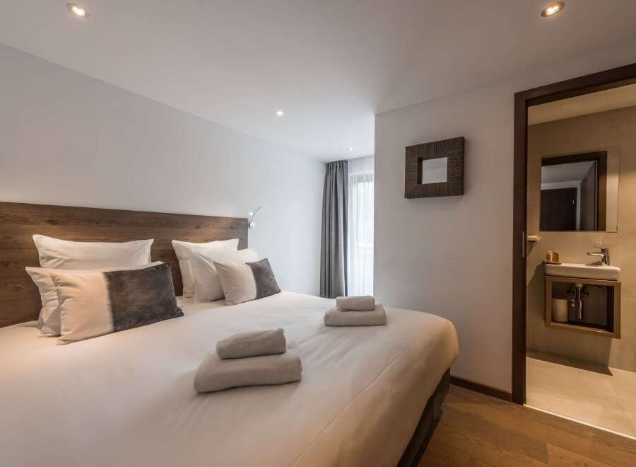 This cozy bedroom features a comfortable bed with plush pillows and fresh towels, perfect for a relaxing stay.