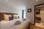 This cozy bedroom features a comfortable bed with plush pillows and fresh towels, perfect for a relaxing stay.