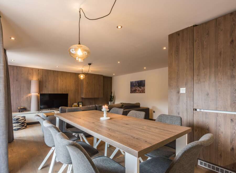 This modern dining area features a stylish wooden table and comfortable gray chairs, perfect for gatherings.