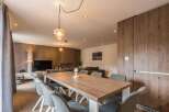 This modern dining area features a stylish wooden table and comfortable gray chairs, perfect for gatherings.