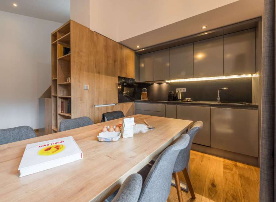 This modern kitchen boasts sleek cabinetry and a spacious wooden dining table, perfect for culinary creations.