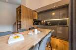 This modern kitchen boasts sleek cabinetry and a spacious wooden dining table, perfect for culinary creations.