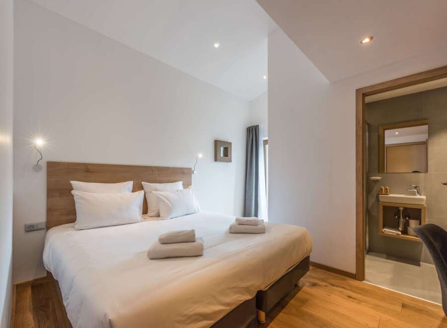Discover a serene bedroom retreat, featuring a comfortable bed with crisp white linens and plush pillows.