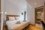 Discover a serene bedroom retreat, featuring a comfortable bed with crisp white linens and plush pillows.