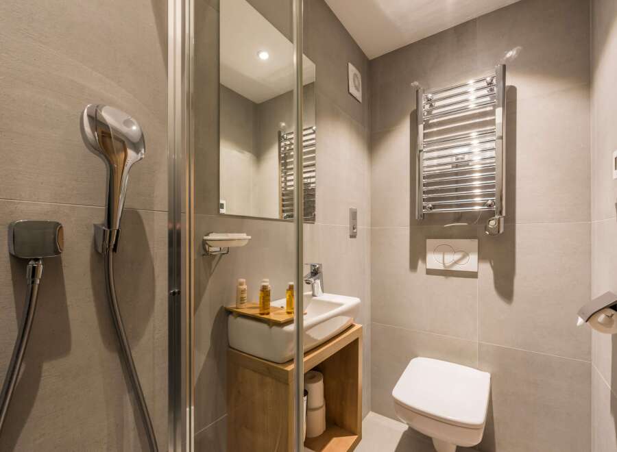 This modern bathroom features a sleek showerhead and a stylish towel warmer.