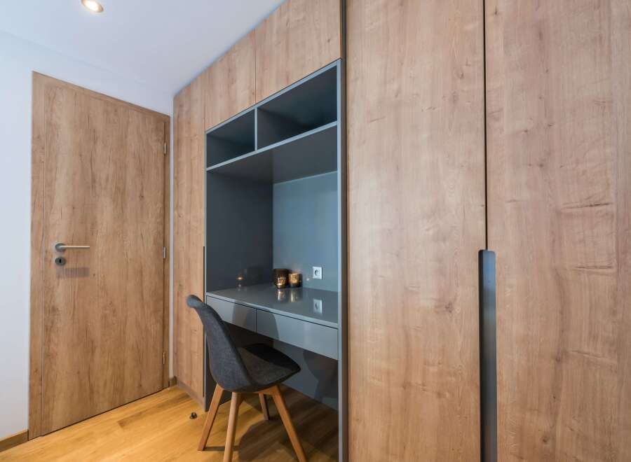 This stylish room features a custom-built desk and shelving unit, perfect for a home office or study space.