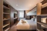 Discover a stylish and modern bedroom featuring a comfortable bed with fresh linens and fluffy pillows.