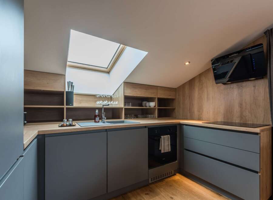 This modern kitchen boasts a sleek design with its gray cabinetry and wooden countertops.