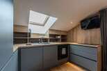This modern kitchen boasts a sleek design with its gray cabinetry and wooden countertops.