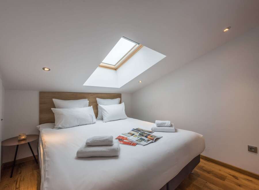 This cozy bedroom features a skylight, allowing natural light to flood the space.