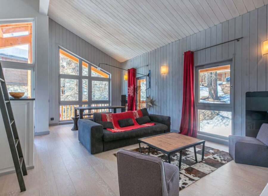 This stunning chalet boasts a spacious open-plan living area with floor-to-ceiling windows offering breathtaking views.