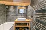 This stunning bathroom boasts a luxurious bathtub, a sleek modern sink with wooden vanity, and a heated towel rack.