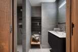 Modern bathroom with gray tile, a walk-in shower, and a floating vanity with a sleek black finish.