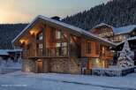 Experience the charm of a cozy wooden chalet nestled in a snowy landscape.
