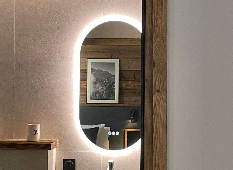 Discover a stylish bathroom with a modern oval mirror and integrated lighting, creating a bright and inviting space.