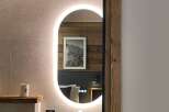 Discover a stylish bathroom with a modern oval mirror and integrated lighting, creating a bright and inviting space.