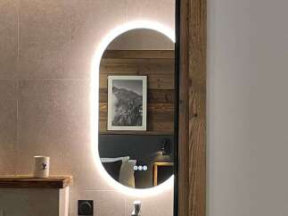 Discover a stylish bathroom with a modern oval mirror and integrated lighting, creating a bright and inviting space.