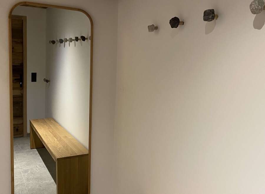 This entryway features a stylish wooden bench and a large mirror, perfect for a quick check before heading out.