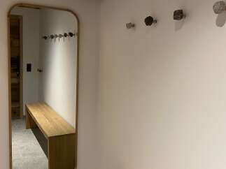 This entryway features a stylish wooden bench and a large mirror, perfect for a quick check before heading out.