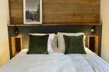 Cozy bedroom with a rustic wooden headboard and a framed black and white picture.