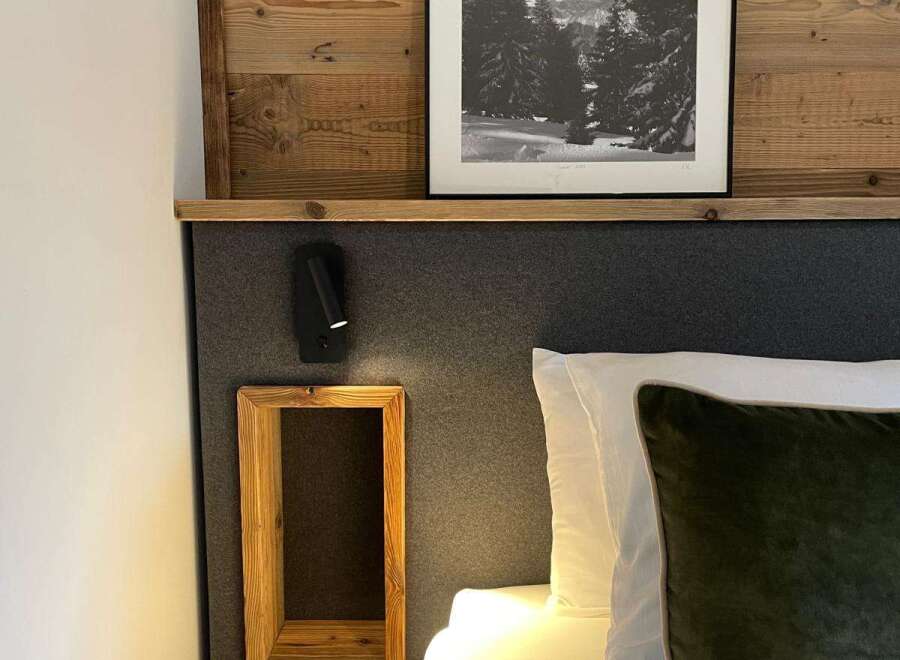 Cozy up in this stylish bedroom featuring a unique wooden headboard and a framed black and white landscape art.