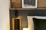 Cozy up in this stylish bedroom featuring a unique wooden headboard and a framed black and white landscape art.