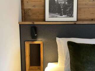 Cozy up in this stylish bedroom featuring a unique wooden headboard and a framed black and white landscape art.