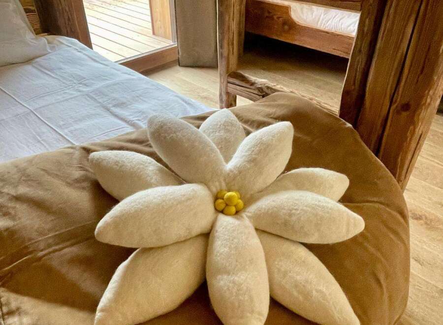 Experience rustic charm in this cozy bedroom, featuring a unique flower-shaped pillow and a comfortable bed.