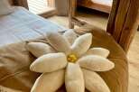 Experience rustic charm in this cozy bedroom, featuring a unique flower-shaped pillow and a comfortable bed.