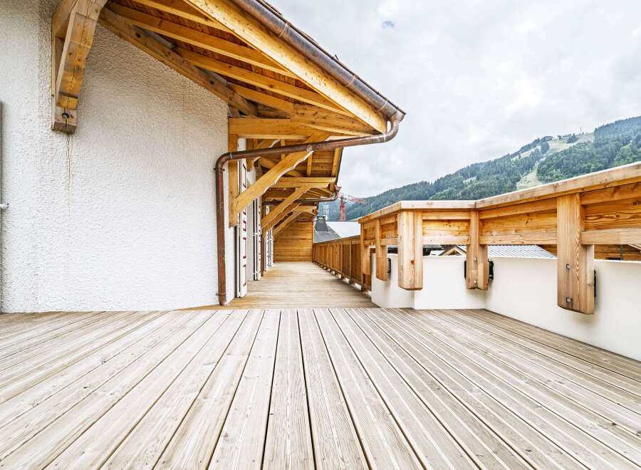Experience the charm of this alpine property with its expansive wooden deck, perfect for enjoying the breathtaking mountain views.