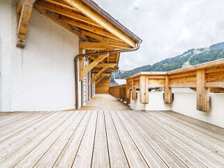 Experience the charm of this alpine property with its expansive wooden deck, perfect for enjoying the breathtaking mountain views.