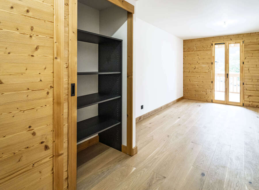 Experience rustic charm in this beautifully appointed room featuring warm, natural wood paneling on the walls and a light-colored hardwood floor.