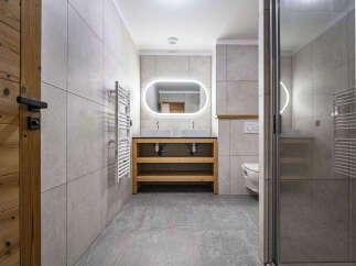 Experience modern comfort in this beautifully appointed bathroom, featuring a sleek double vanity with vessel sinks and a striking illuminated mirror.