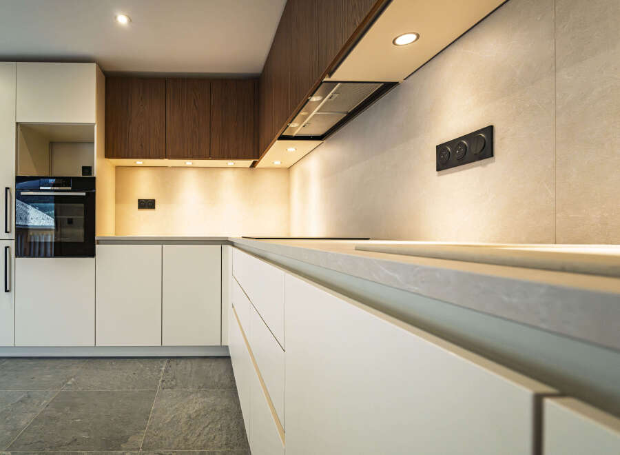 Experience modern luxury in this sleek kitchen, featuring minimalist white cabinetry and warm wood accents.