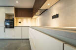 Experience modern luxury in this sleek kitchen, featuring minimalist white cabinetry and warm wood accents.