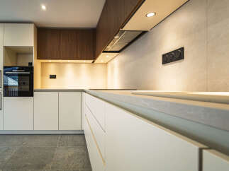 Experience modern luxury in this sleek kitchen, featuring minimalist white cabinetry and warm wood accents.