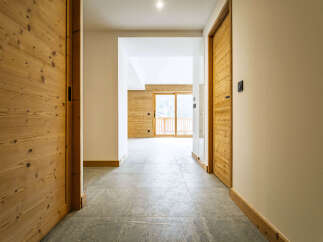 Step into this modern mountain retreat featuring warm wooden doors and accents that complement the sleek, large-format tile flooring.