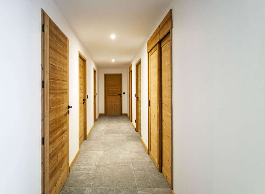 Step into this inviting hallway featuring warm wooden doors and a sleek, modern design.