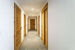 Step into this inviting hallway featuring warm wooden doors and a sleek, modern design.