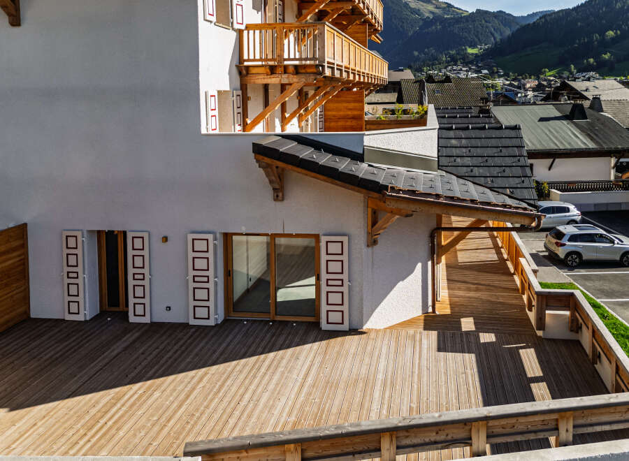 Experience modern alpine living in this stunning property featuring a spacious wooden deck perfect for outdoor relaxation and entertaining.