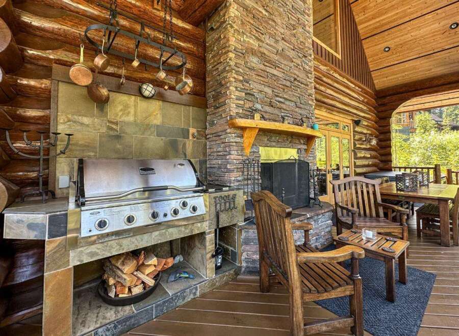 Experience luxury living in this stunning log cabin, featuring an outdoor kitchen with a built-in grill and a cozy fireplace.