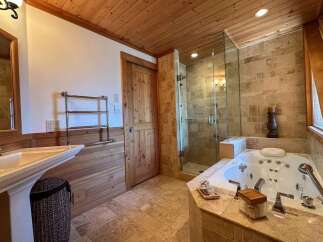 Step into luxury with this stunning bathroom! Featuring a spa-like jacuzzi tub, a separate glass-enclosed shower, and elegant wooden accents throughout.