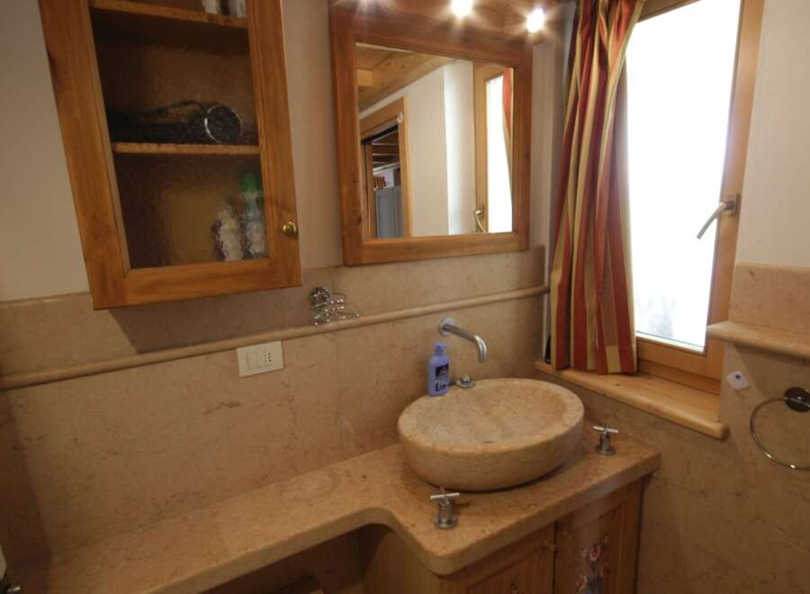 This charming bathroom features a unique stone sink and a wooden vanity, creating a warm and inviting atmosphere.