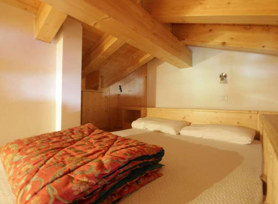 Discover a cozy bedroom with a unique wooden ceiling and a comfortable bed.