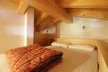 Discover a cozy bedroom with a unique wooden ceiling and a comfortable bed.