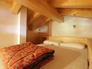 Discover a cozy bedroom with a unique wooden ceiling and a comfortable bed.
